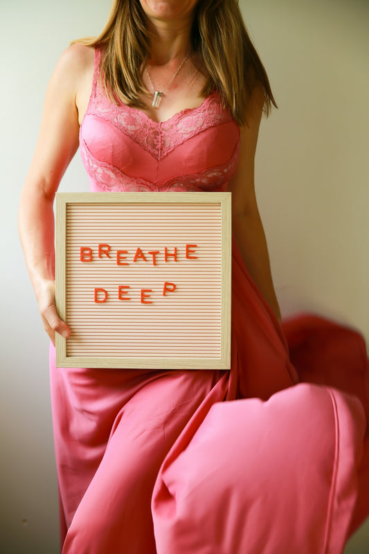 Woman holds a sign saying breathe deep.
