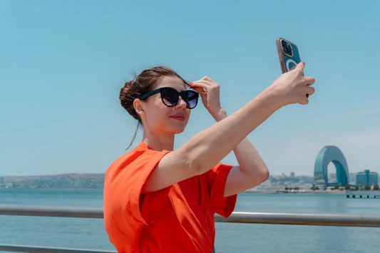 Woman taking a selfie with ocean and city background